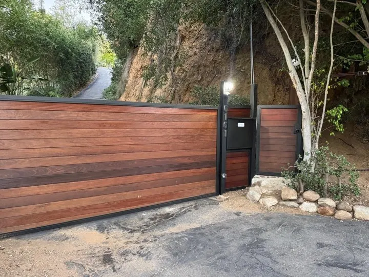 Matching pedestrian entry beside the wood-toned driveway gate