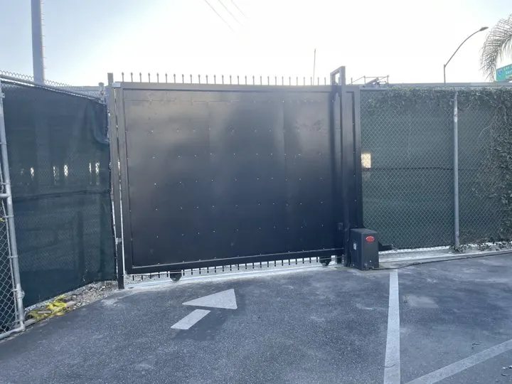 Closed screened vehicle gate beside mesh fencing