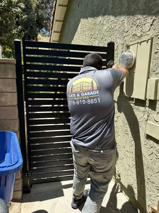 Technician working at the photographed black slat side gate.