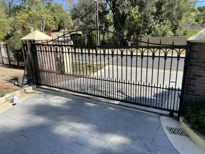 Straight-top decorative driveway gate between masonry piers.